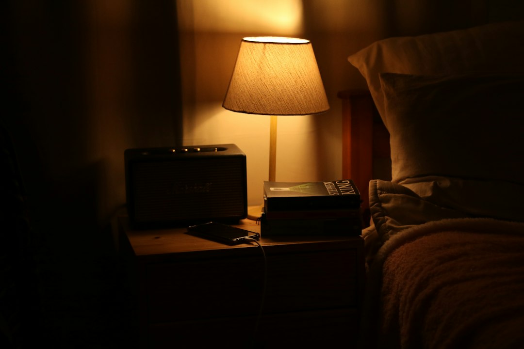 A bedside lamp illuminates a nightstand with a radio