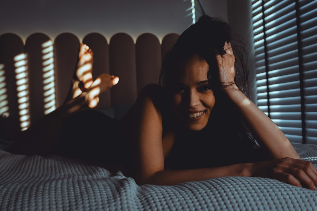 Smiling woman lying on bed with striped light